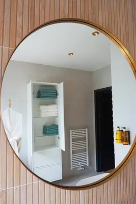 a mirror reflecting a bathroom with a shelf and towels at B&B by Delizia met mogelijkheid tot bijhuren van privé wellness in Rumst