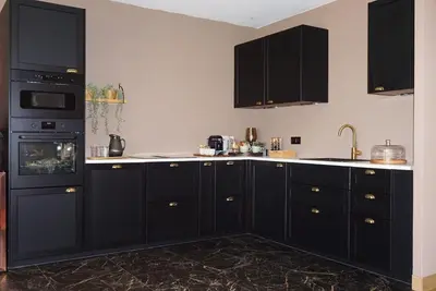 a kitchen with black cabinets and a black refrigerator at B&B by Delizia met mogelijkheid tot bijhuren van privé wellness in Rumst