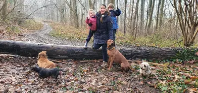 a woman and two children are standing in the woods with dogs at Guesthouse Biolleke in Boutersem