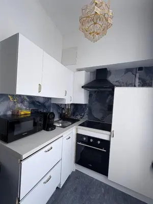 a kitchen with white cabinets and a chandelier at Hôtel Garden's jacuzzi spa 1 in Brussels