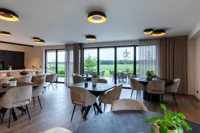 a restaurant with tables and chairs and large windows at Logies De Hoeven in Kasterlee