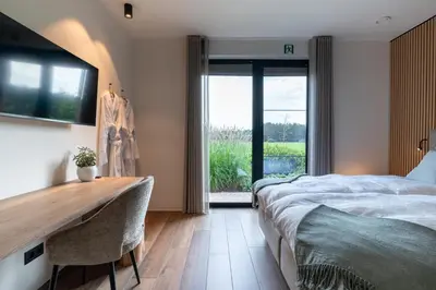 a bedroom with a bed and a desk and a window at Logies De Hoeven in Kasterlee