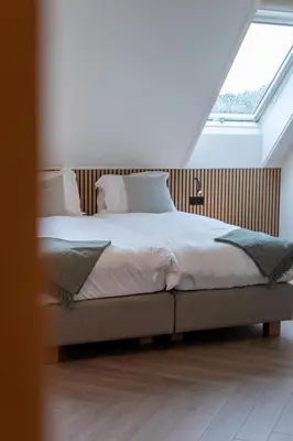 a bedroom with a large bed with a window at Logies De Hoeven in Kasterlee
