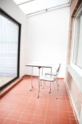 a table and a chair in a room with a window at Tumaini House in Antwerp