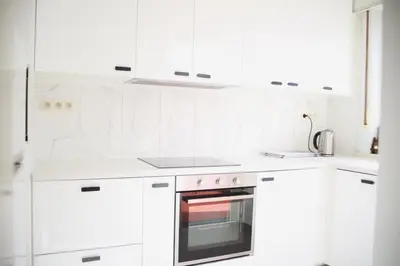 a white kitchen with white cabinets and an oven at Tumaini House in Antwerp