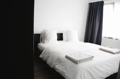 a white bed with two towels on top of it at Tumaini House in Antwerp
