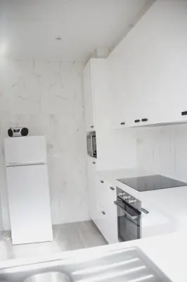 a white kitchen with a sink and a refrigerator at Tumaini House in Antwerp
