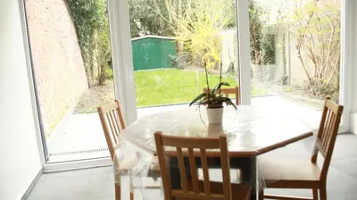 a dining room with a table and chairs and a window at Tumaini House in Antwerp