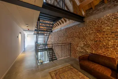 a brick wall with a staircase and a couch at Pachthof 1860 in Sint-Pieters-Leeuw