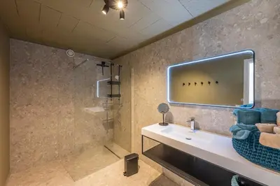 a bathroom with a sink and a shower with a mirror at Pachthof 1860 in Sint-Pieters-Leeuw