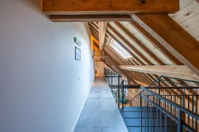 an attic hallway with wooden ceilings and blue stairs at Pachthof 1860 in Sint-Pieters-Leeuw