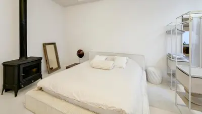 a white bedroom with a bed and a stove at Spacious loft near City Centre, Luce CasaMia in Antwerp
