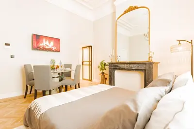 a bedroom with a bed and a table and a fireplace at Elégance du Quartier Européen Parking gratuit in Brussels