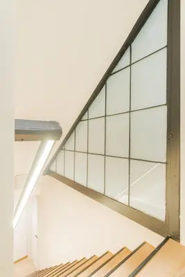 a glass staircase in a white room with a window at Elégance du Quartier Européen Parking gratuit in Brussels