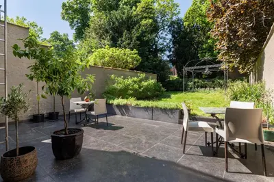 a patio with chairs and a table and a tree at Boutique Baron Osy Suite First Terrace in Antwerp