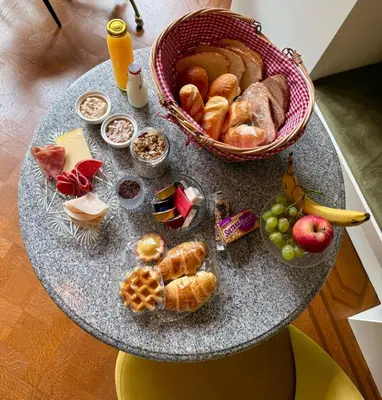 a table with a basket of bread and pastries on it at Boutique Baron Osy Suite First Terrace in Antwerp