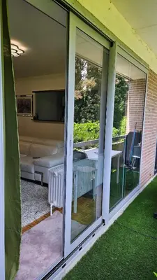 a screened porch with sliding glass doors and a television at Chambre meublée chez l'habitant a uccle in Brussels