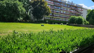 a large building with a field of grass in front of a building at Chambre meublée chez l'habitant a uccle in Brussels