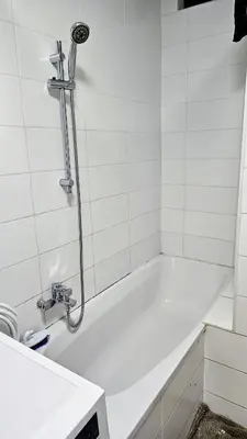 a white bath tub in a white tiled bathroom at Chambre meublée chez l'habitant a uccle in Brussels