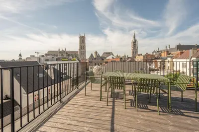 a deck with a table and chairs on a balcony at Cosy Studio with Spectacular View from the Rooftop in Ghent