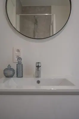 a bathroom sink with a round mirror above it at Cosy Studio with Spectacular View from the Rooftop in Ghent