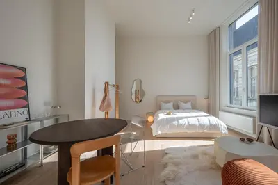 a white bedroom with a bed and a table at Cosy Studio with Spectacular View from the Rooftop in Ghent