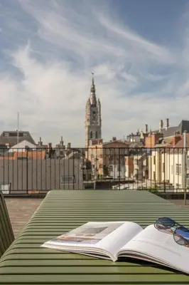 an open book on a table with a clock tower at Cosy Studio with Spectacular View from the Rooftop in Ghent