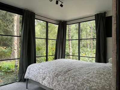 a bedroom with a bed and large windows at TerraVenturia - Natura Pirsch in Rixensart
