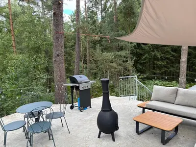 a grill on a patio with chairs and a couch at TerraVenturia - Natura Pirsch in Rixensart