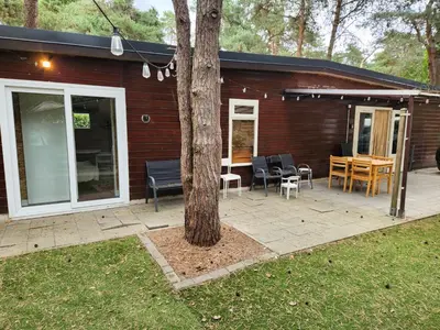 a patio with a table and chairs and a tree at Chalet Balen in Balen