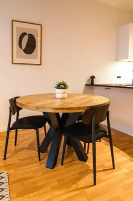 a wooden table with black chairs and a table with a plant at Modern Comfort - Bus & Tram at Door in Antwerp