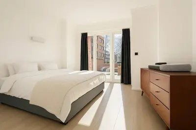 a bedroom with a bed and a dresser and a window at Cozy Family Apartment - Bus & Tram Right in Front in Antwerp