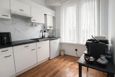 a kitchen with white cabinets and a wooden floor at Cozy & Relaxing Apartment - Bus & Tram at Door in Antwerp