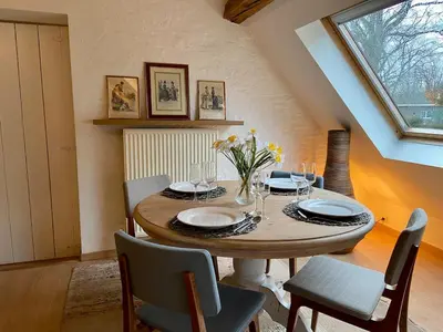 a dining room with a wooden table and chairs at Romantic Loft, historic farmhouse, Sauna, Nature walks in Schilde