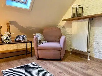 a living room with a chair and a table at Romantic Loft, historic farmhouse, Sauna, Nature walks in Schilde