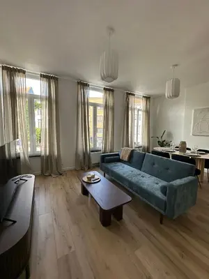 a living room with a blue couch and a table at 1- Nid lumineux 2 chambres au coeur d'Ixelles in Brussels