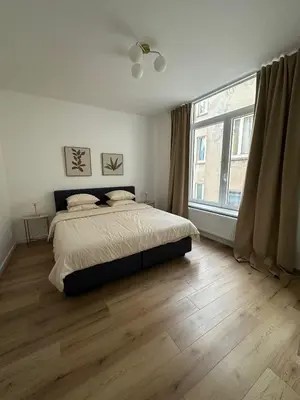 a bedroom with a bed and a large window at 1- Nid lumineux 2 chambres au coeur d'Ixelles in Brussels