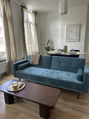 a blue couch in a living room with a coffee table at 1- Nid lumineux 2 chambres au coeur d'Ixelles in Brussels