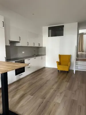 an empty kitchen with a yellow chair in a room at 1- Nid lumineux 2 chambres au coeur d'Ixelles in Brussels