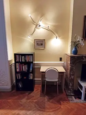 a table and a chair in a room with a book shelf at Bright 1BR with terrace near Montgomery in Brussels