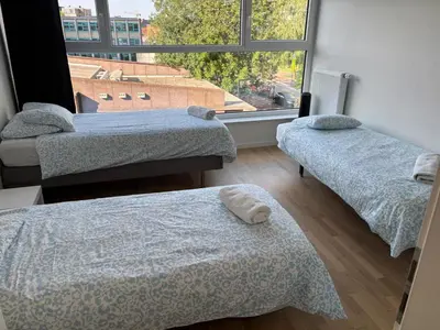a room with two beds and a large window at Modern City Apartment Close to Everything in Brussels