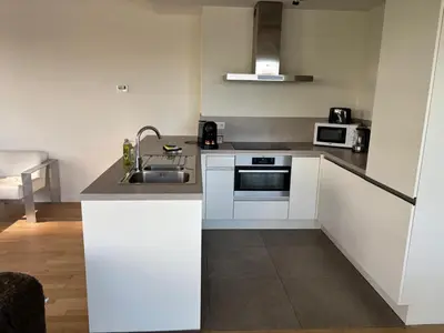 a white kitchen with a sink and a microwave at Modern City Apartment Close to Everything in Brussels