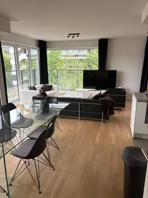 a living room with a couch and a table and chairs at Modern City Apartment Close to Everything in Brussels