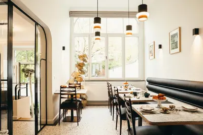 a dining room with tables and chairs and a window at La Villa Maurice in Brussels