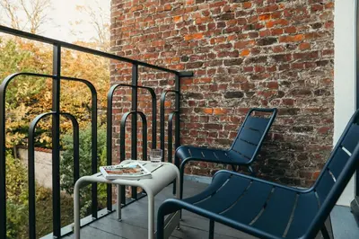 two chairs and a table on a balcony with a brick wall at La Villa Maurice in Brussels