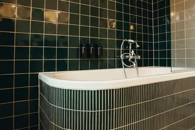 a bath tub in a green tiled bathroom at La Villa Maurice in Brussels