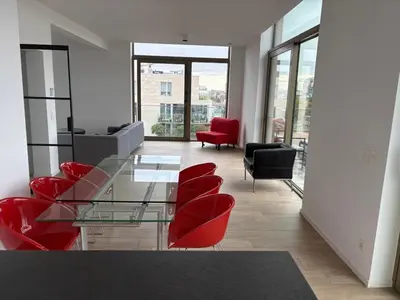 a living room with a glass table and red chairs at Top floor luxury with spectacular water views in Brussels