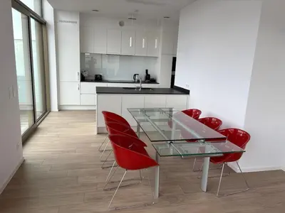 a kitchen with a glass table and red chairs at Top floor luxury with spectacular water views in Brussels