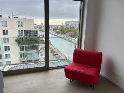 a red chair sitting in front of a large window at Top floor luxury with spectacular water views in Brussels