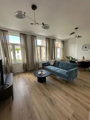 a living room with a blue couch and a table at 2- Nid lumineux 1 chambres au coeur d'Ixelles in Brussels